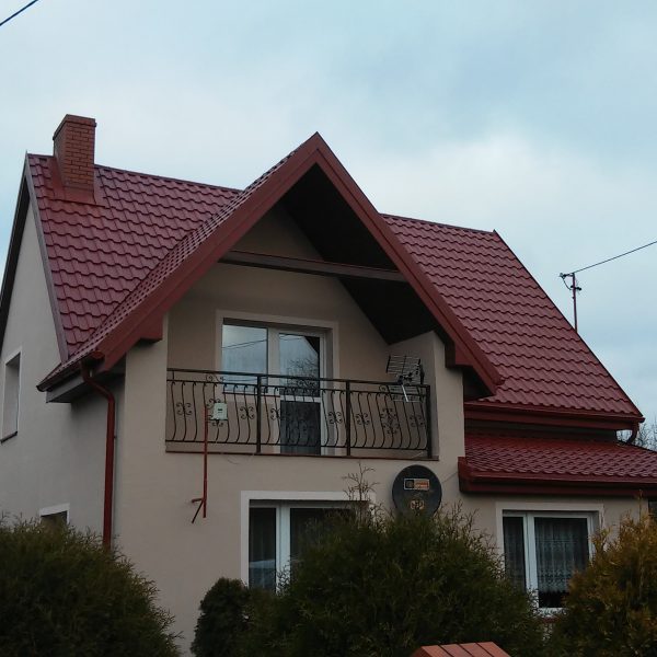 Wiśniowa blachodachówka Ruukki Adamante Purex na dachu o wyrazistej, falistej formie.