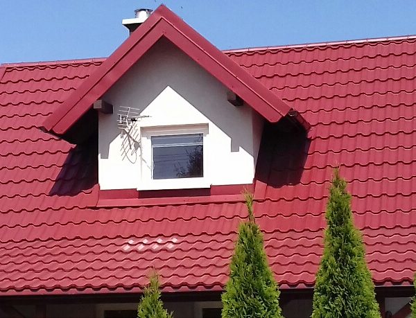 Pokrycie dachu blachodachówką Ruukki Finnera w intensywnym kolorze wiśni.