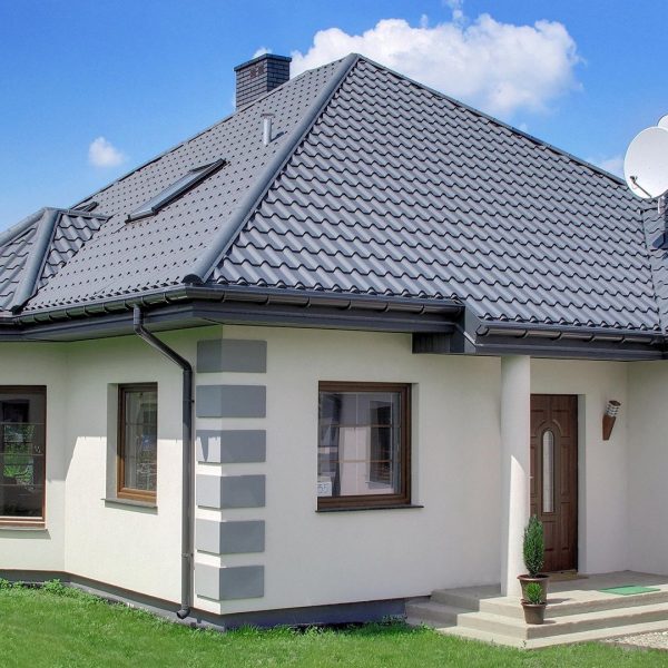 Pokrycie dachowe Budmat Aria – blachodachówka w kolorze grafitowym na nowoczesnym budynku.”