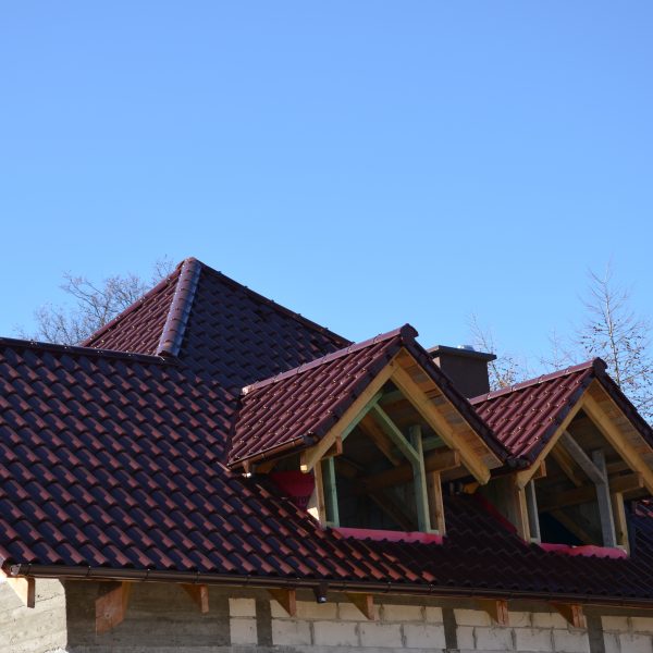 Estetyczny dach z dachówką ceramiczną Creaton Symfonie czerwień winna na budynku w stanie surowym – solidna baza pod wykończenie elewacji.