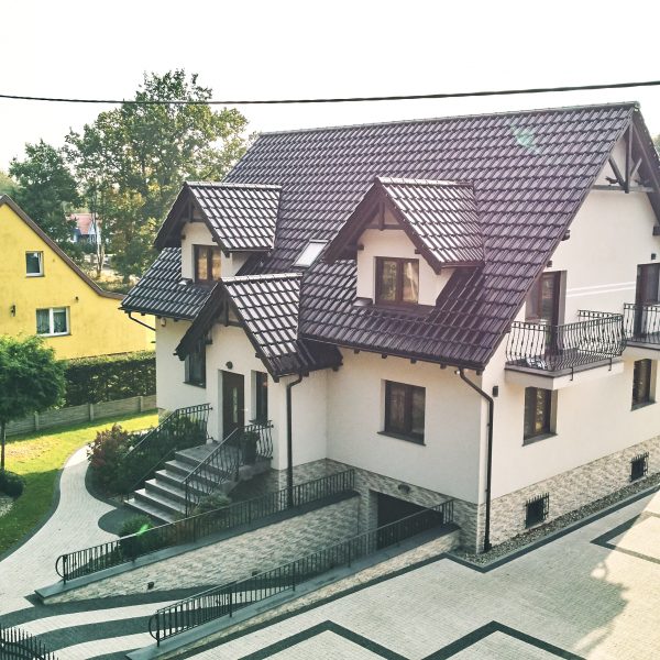 Zdjęcie lotnicze przedstawiające dach z połyskującą dachówką Creaton Titania brąz glazura.