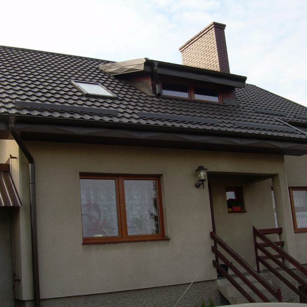 Dom jednorodzinny z dachem pokrytym blachodachówką modułową Ruukki Finnera w kolorze brązowym. Dach ma nowoczesny wygląd z widocznym połyskiem i zintegrowanym systemem rynnowym.