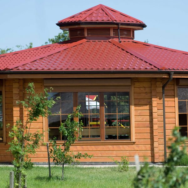 Dach w kolorze wiśniowym z blachodachówki Ruukki Monterrey – doskonałe dopasowanie do drewnianej architektury