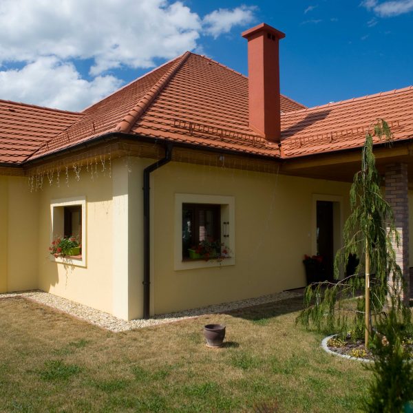 Dach z dachówki Wienerberger karpiówka Natura na domu z żółtą elewacją i trawnikiem dookoła domu