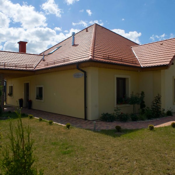 Dach z dachówki Wienerberger karpiówka Natura na domu z żółtą elewacją i trawnikiem dookoła domu
