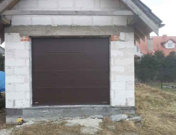 Brama segmentowa bez przetłoczeń w kolorze brąz, nadająca budynkowi ciepły i elegancki wygląd.