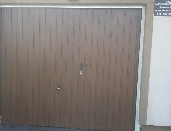 Realizacja z bramą uchylną w odcieniu orzecha, nadającą ciepły, klasyczny wygląd.