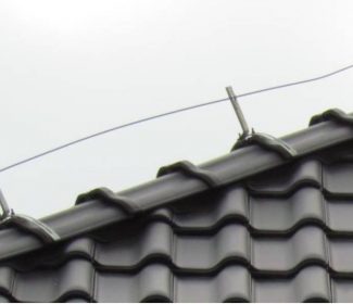 Elementy systemu odgromowego zamontowane na gąsiorze dachu, zapewniające ochronę budynku przed wyładowaniami atmosferycznymi